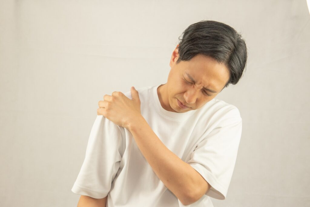 筋肉痛で肩を押さえる男性